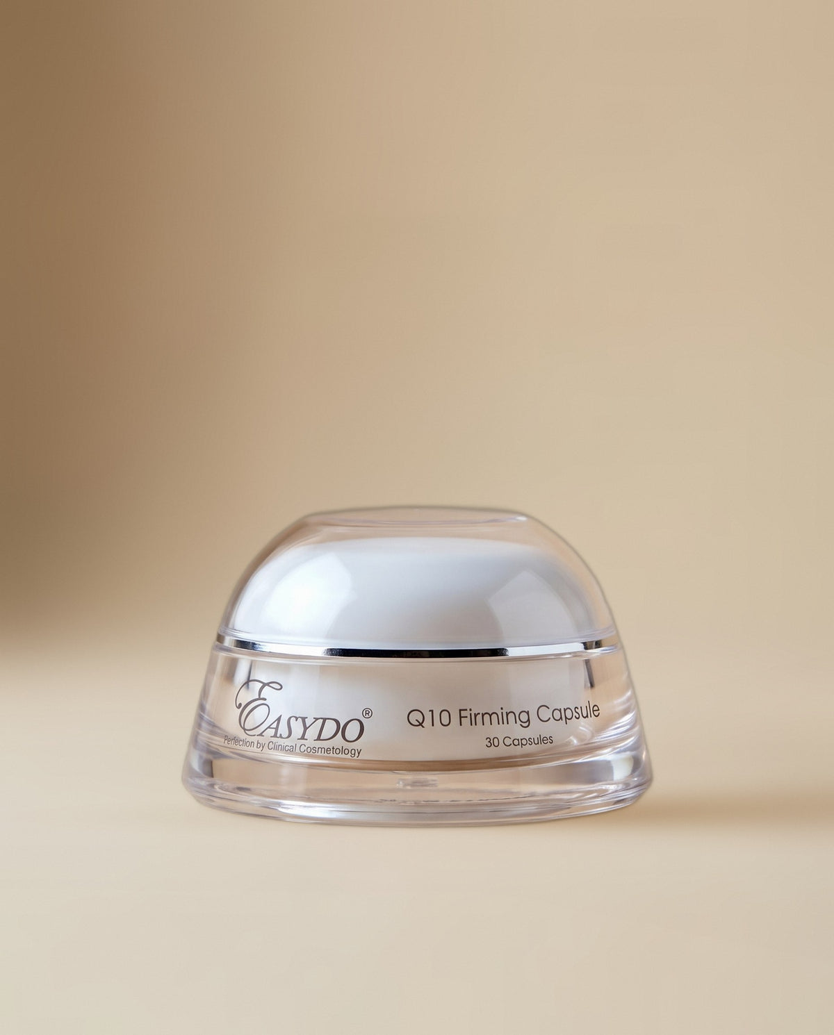 A clear cosmetic jar with a white lid and a transparent cap, labeled 'EASYDO Q10 Firming Capsule 30 Capsules', set against a solid beige background.