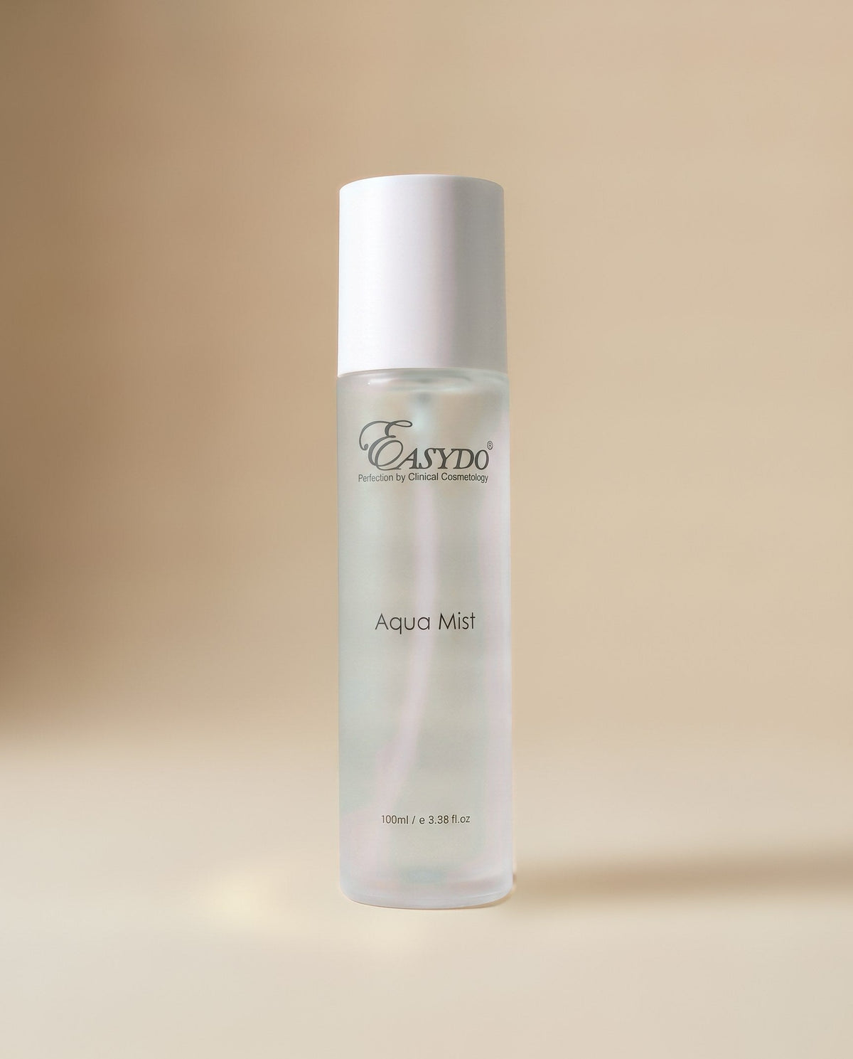 A 100ml clear bottle of EASYDO Aqua Mist with a white cap, standing on a beige surface against a matching beige background.