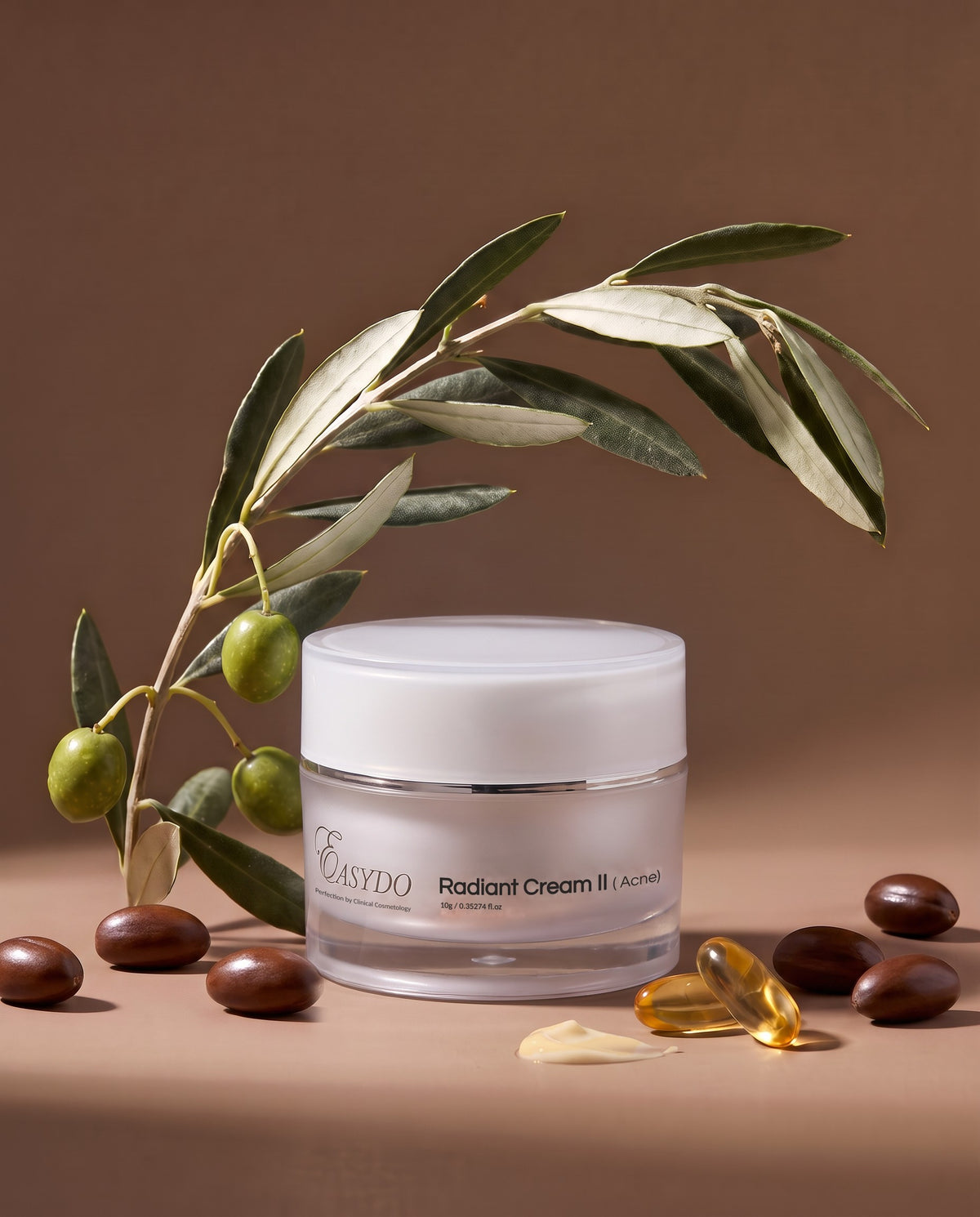 A jar of EASYDO Radiant Cream II skincare product on a warm brown background, styled with olive branches, whole olives, and a translucent yellow capsule.